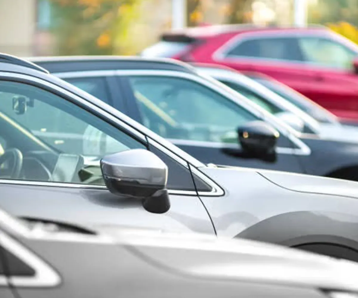 Row of parked cars in a parking lot, viewed from the side with focus on the wing mirrors.